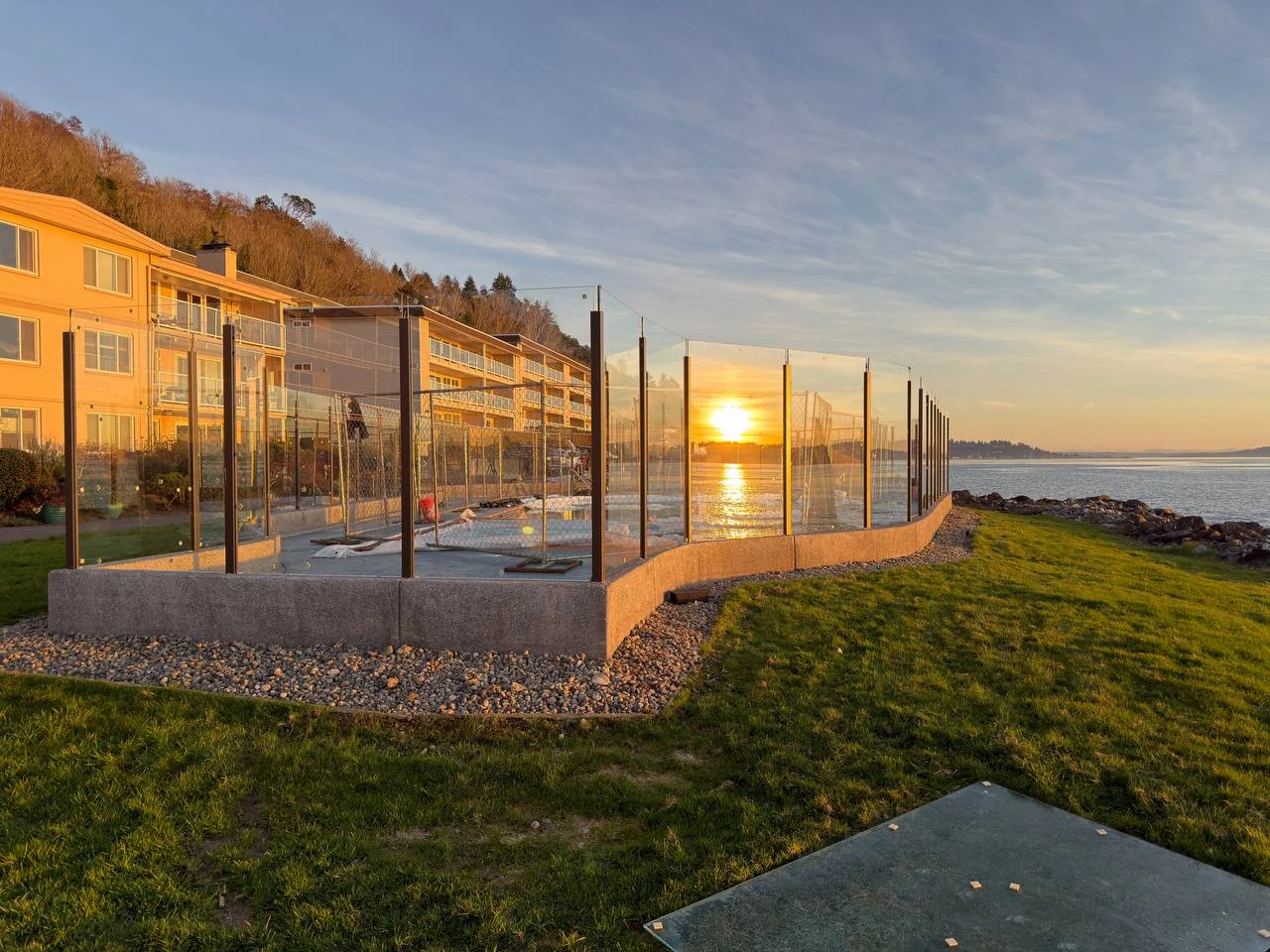 Glass railing overlooking the water at sunset